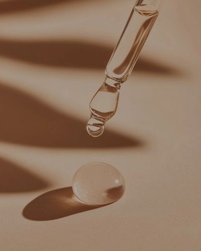 Close-up of a dropper releasing a droplet onto a smooth surface.