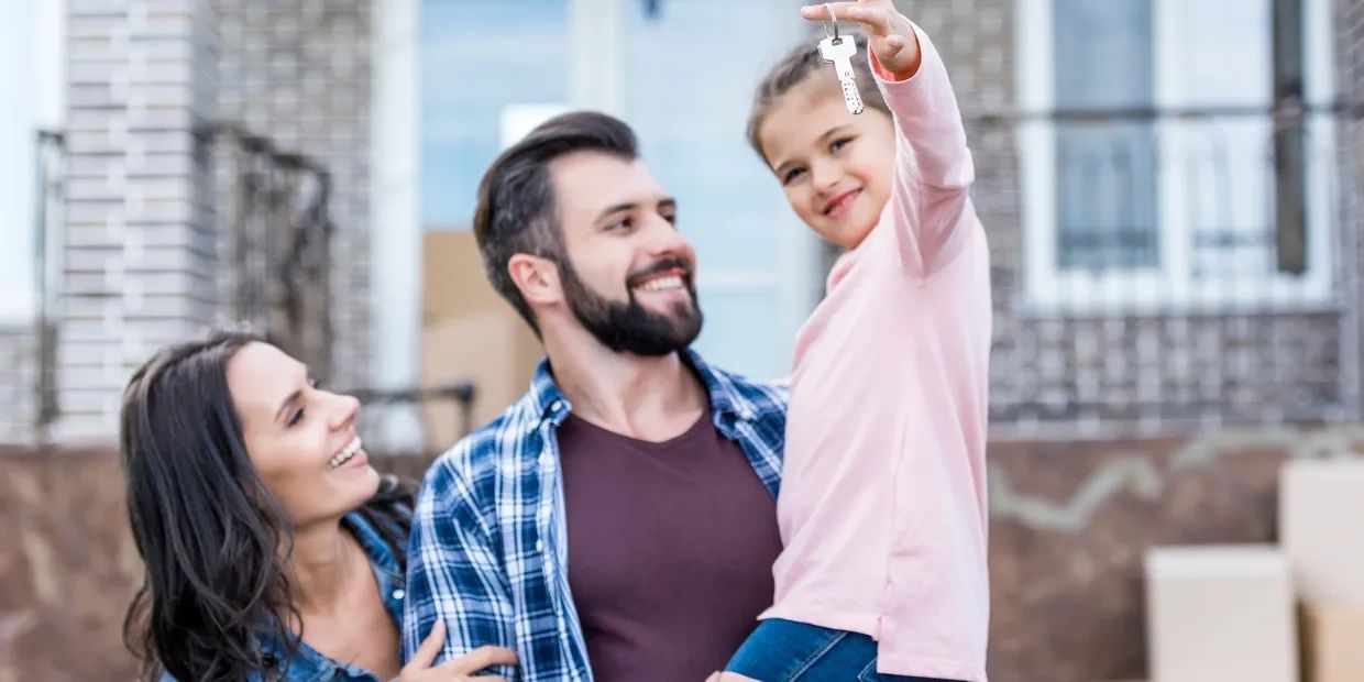 Happy family holding house key outside new home.