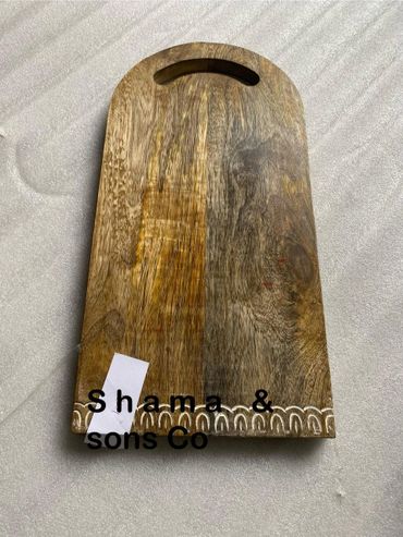 Wooden cutting board with handle and decorative edge.