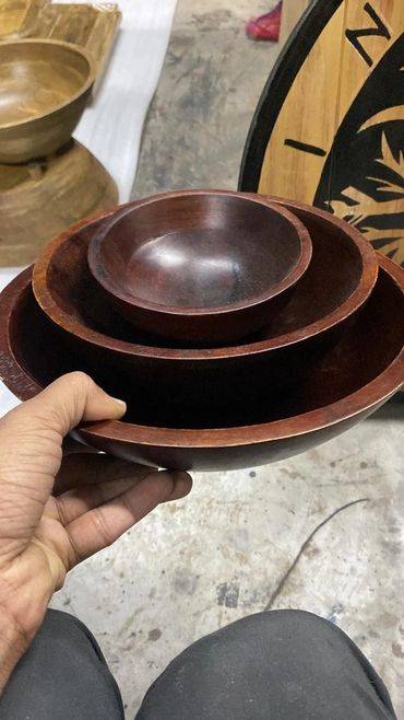 Hand holding a set of three nested wooden bowls.