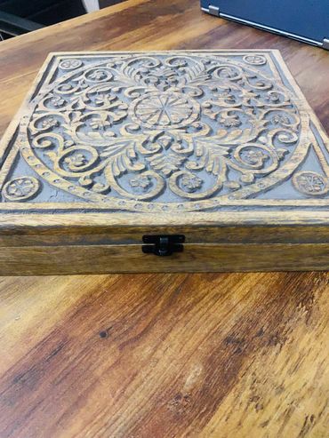 Ornate wooden box with intricate carved floral and scroll designs.