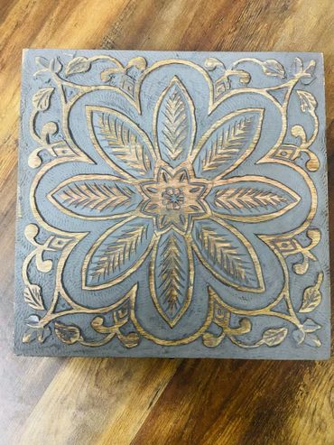 Wooden square with intricate floral carving and leaf patterns.