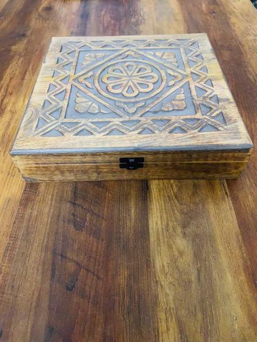 Decorative wooden box with intricate geometric carvings on a wooden table.