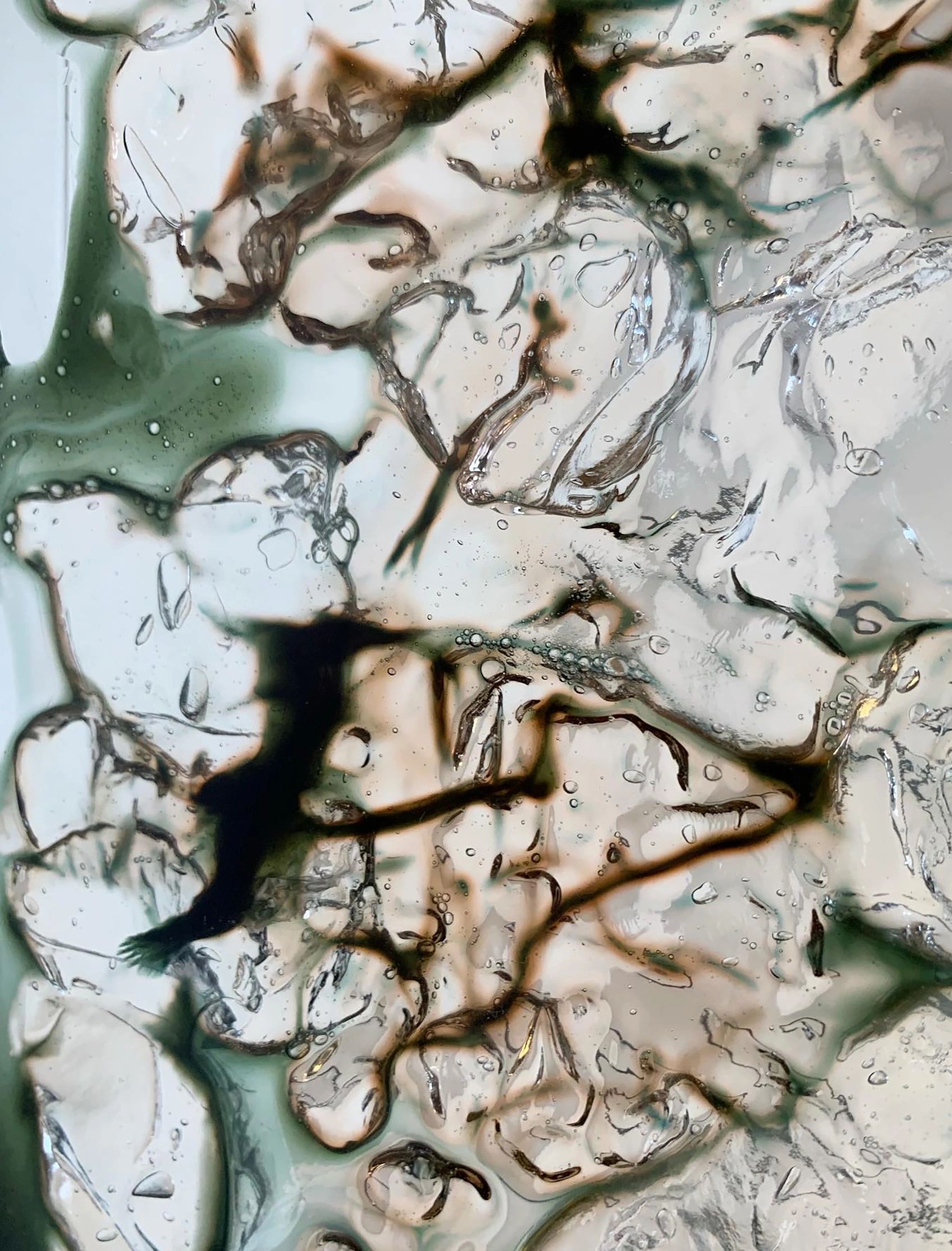 Close-up of translucent gel with dark veins and bubbles.