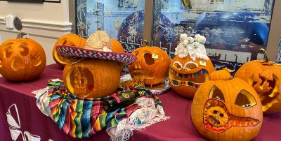 Decorated pumpkins with various carved faces and a sombrero on one, displayed on a table.