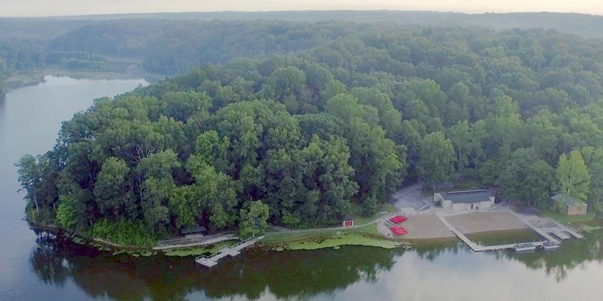 Aerial view of a forested peninsula with a lake and docks.