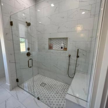 Modern marble shower with glass enclosure and built-in bench.