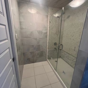 Modern bathroom with glass shower enclosure and tiled walls.