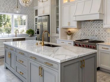 Elegant kitchen with marble island and gold fixtures.
