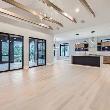 Spacious modern living area with wooden beams and large glass doors.