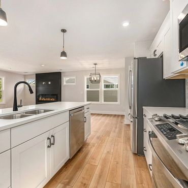 Modern kitchen with white cabinets, stainless steel appliances, and wooden flooring.