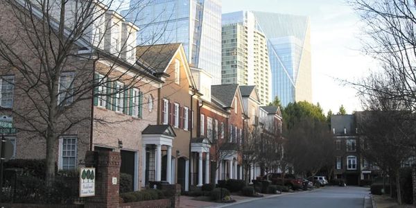 Row of traditional townhouses with modern skyscrapers in the background.