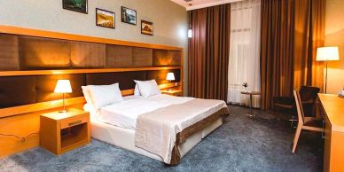 Modern hotel room with a large bed and warm lighting.