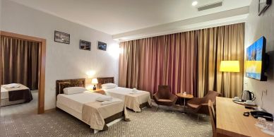 Hotel room with two beds and cozy seating area.