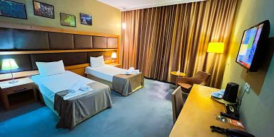 Hotel room with two single beds and warm lighting.