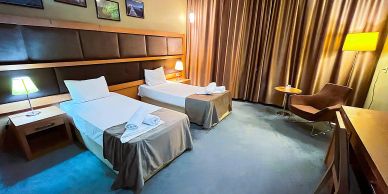 Hotel room with two single beds and warm lighting.