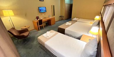 Hotel room with three single beds and a TV.