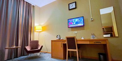 Hotel room with workspace and seating area.