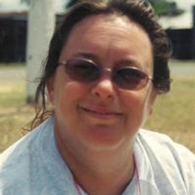 Woman wearing sunglasses and smiling outdoors.