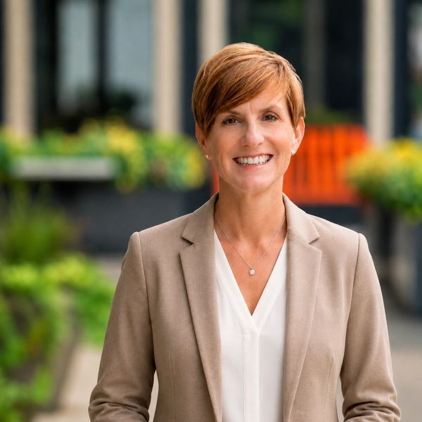 Confident woman in business attire smiling outdoors.