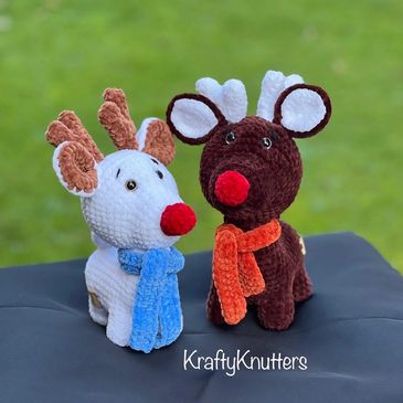 two handmade crochet reindeer, one white and one brown, both with scarves and red noses