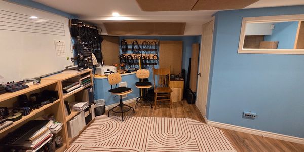 Organized music studio with chairs, shelves, and equipment against blue walls.