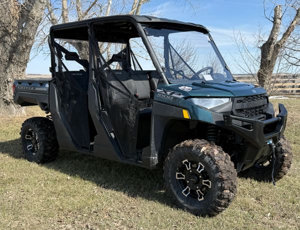 A rugged Polaris off-road utility vehicle parked on grass under leafless trees.