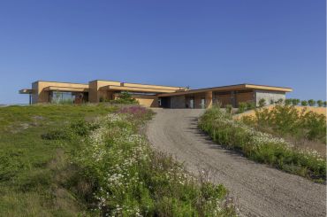 Modern house on a hillside with a gravel driveway.