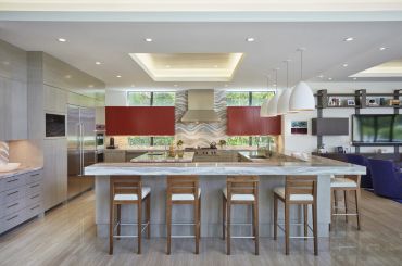 Modern kitchen with marble island and wooden stools.