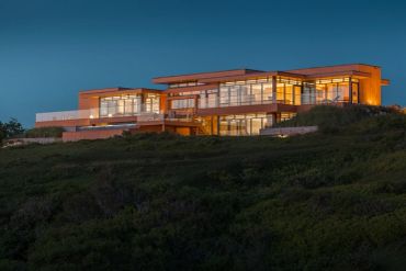 Modern house lit up at dusk.