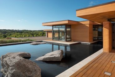 Modern house with wooden deck and water feature.