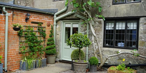 Cozy courtyard with potted plants and a green door on a rustic stone and brick house.