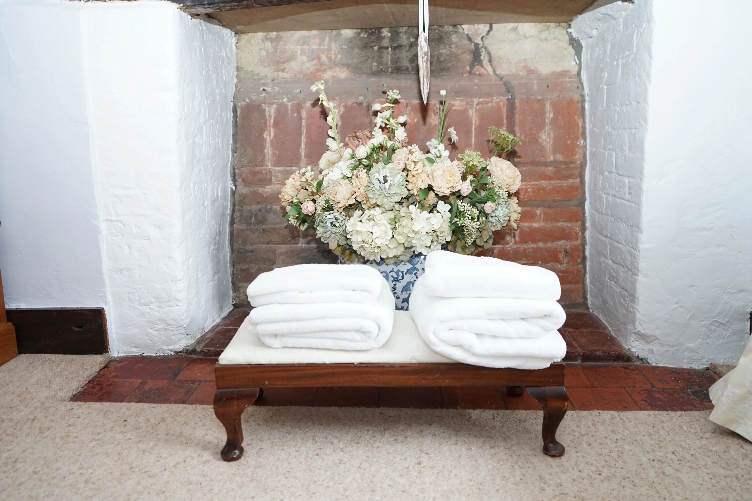 White towels folded on a wooden bench with flowers in the background.