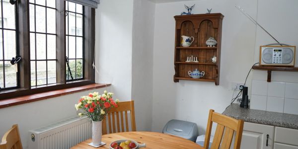 Cozy kitchen corner with wooden table, flowers, and vintage decor.