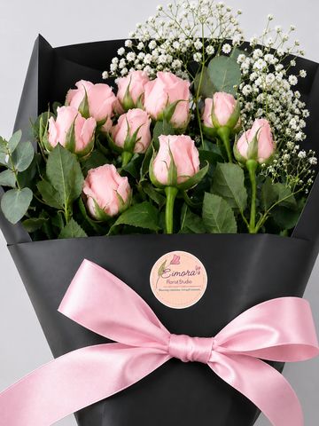 Elegant bouquet of pink roses wrapped in black paper with a pink ribbon.