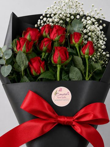 Bouquet of red roses with white baby's breath wrapped in black paper and tied with a red ribbon.