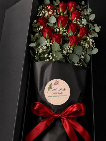Elegant bouquet of red roses with greenery in a black box.