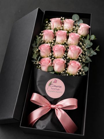 Elegant bouquet of pink roses in a black gift box with a satin ribbon.