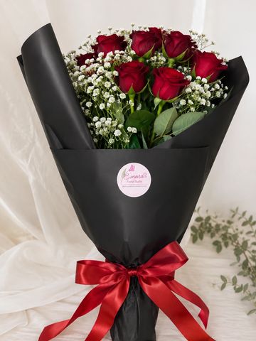 Elegant bouquet of red roses wrapped in black paper with a red ribbon.