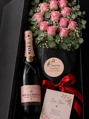 Gift box with pink roses, champagne, and a greeting card.