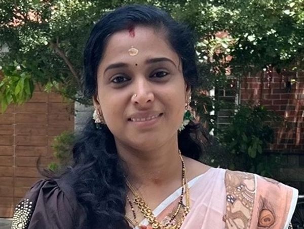 A woman in traditional attire smiling outdoors.