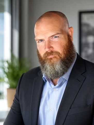 Bearded man in suit with intense gaze.