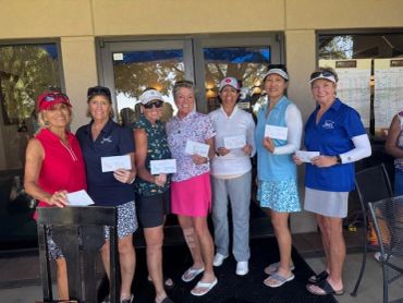 Group of women holding envelopes and smiling outdoors.