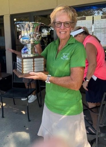 Woman holding a large trophy and smiling.