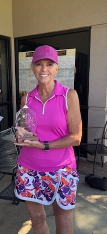 Woman in pink athletic wear holding a glass trophy.