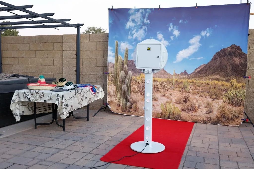 A digital Photobooth with a desert backdrop, and a table full of props.