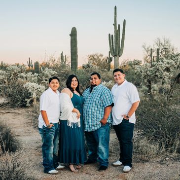 A family of four posing in a desert landscape with cacti.