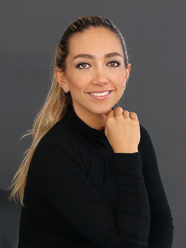 Smiling woman in a black turtleneck posing against a gray background.