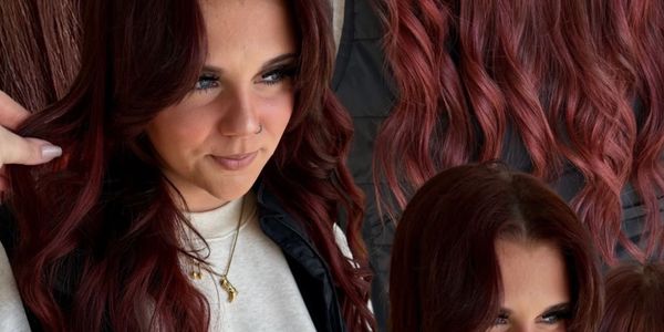 Woman with long, wavy burgundy hair showcasing her hairstyle.