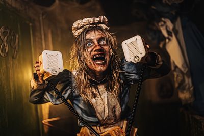 Creepy horror character holding two old telephones.